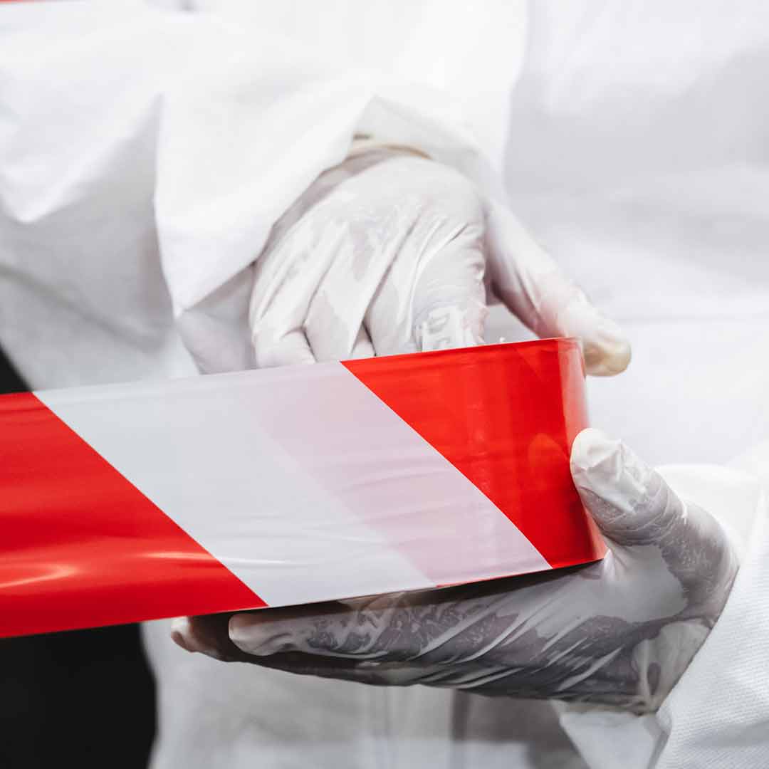 Hazmat worker holding red warning tape