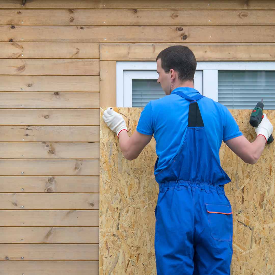 Worker boarding up damaged home window
