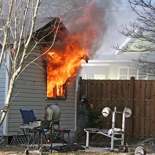 House fire with flames and smoke behind fence
