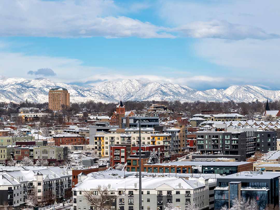 Snow-covered Denver city skyline with mountains in background