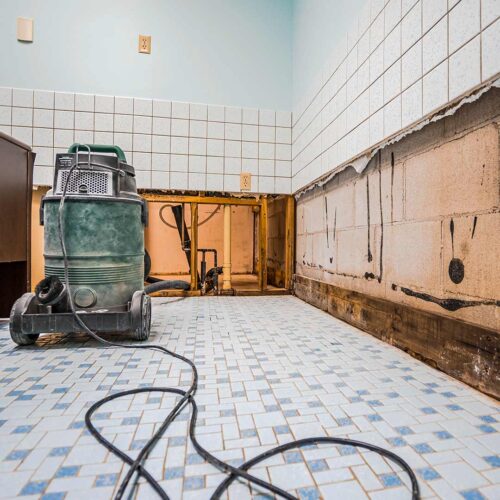 Flood damage cleanup with water extraction equipment and exposed walls after water removal